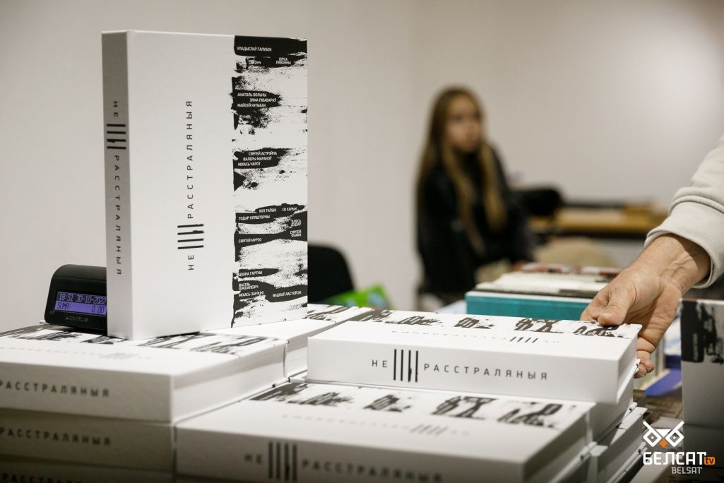 Мужчына цягнецца да новага выдання кнігі «(Не)расстраляныя» з сабранымі гісторыямі жыцця беларускіх пісьменнікаў, якія сталіся ахвярамі сталінскіх рэпрэсіяў. Варшава, Польшча. 30 кастрычніка 2022 года. (Фота: Белсат)