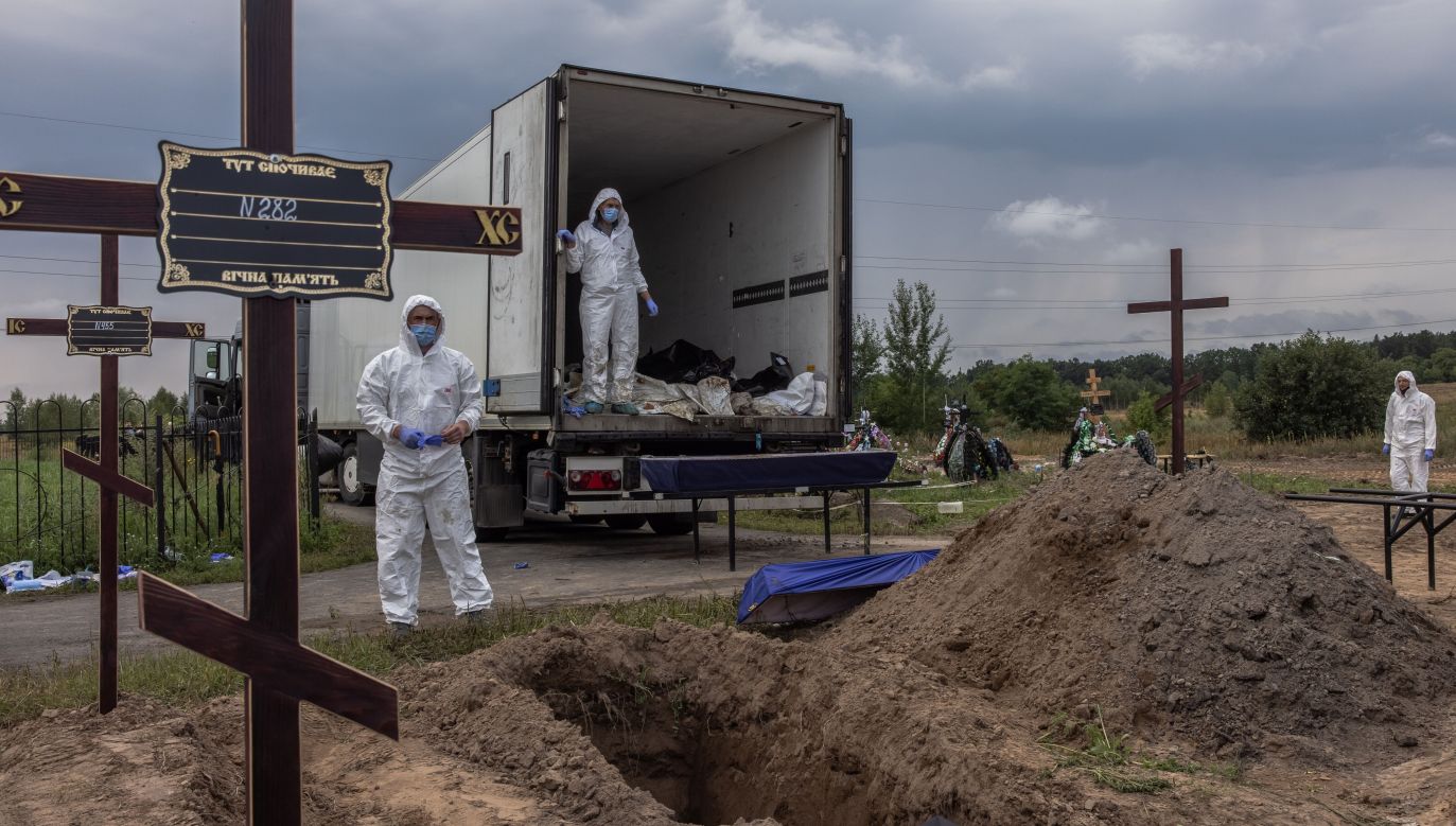 Workers place mortal remains in coffins of unidentified persons killed in the Bucha district at the time of the Russian occupation, during the mass burial at a cemetery in Bucha, northwest of Kyiv, Ukraine, 11 August 2022. Photo: PAP/EPA