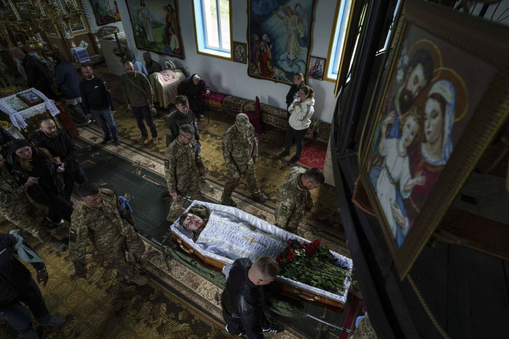 Ганаровая варта нясе труну з целам украінскага вайскоўца Дмытра Шапавалава падчас развітання ў царкве сяла Ёсыпаўка Вінніцкай вобласці. Дмытро стаў шырока вядомы ў 2023 годзе з кадраў, на якіх каштаваў яблык упершыню пасля года ў расейскім палоне. 9 чэрвеня 2025-га ў Дмытра спынілася сэрца. Ёсыпаўка, Украіна. 13 чэрвеня 2025 года. Фота: Evgeniy Maloletka / AP Photo / East News