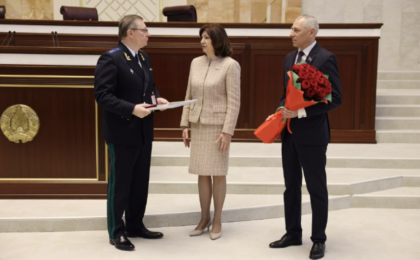 Злева направа: Андрэй Швед (злева) атрымлівае ганаровую грамату за забеспячэнне правоў і свабод грамадзянаў» ад Наталлі Качанавай (у цэнтры). (Фота: Prokuraturabelarus / Telegram)