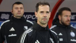 Tymczasowy trener Legii Warszawa Inaki Astiz (fot. PAP) Portret Hiszpana Inakiego Astiza, tymczasowego trenera Legii Warszawa, stojącego na pierwszym planie na ławce rezerwowych w czarnej kurtce z herbem klubu, z dwoma innymi członkami sztabu szkoleniowego w tle.