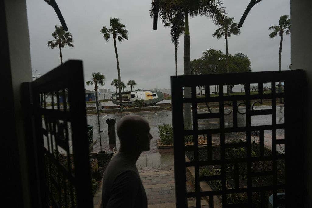 Жыхар гораду Галфпорт (Gulfport) рыхтуецца да ўрагану Мілтан на фоне чоўна, перавернутага ўраганам Гэлен. Галфпорт, Флорыда, ЗША. 9 кастрычніка 2024 года. Фота: Rebecca Blackwell / AP / East News