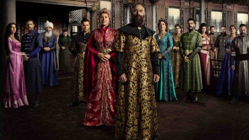 Plakat serialu „Wspaniałe stulecie” z głównymi bohaterami w strojach osmańskich. W centrum Halit Ergenç jako sułtan Sulejman Wspaniały i Meryem Uzerli jako Hürrem Sultan. Cała obsada przedstawiona jest w pałacowych wnętrzach Topkapi