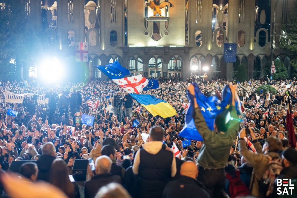 Дэманстранты скандуюць лозунгі, трымаючы сцягі ЕЗ і Грузіі, падчас мітынгу апазіцыі перад будынкам парламента. Тбілісі, Грузія. 28 кастрычніка 2024 года. Фота: Белсат