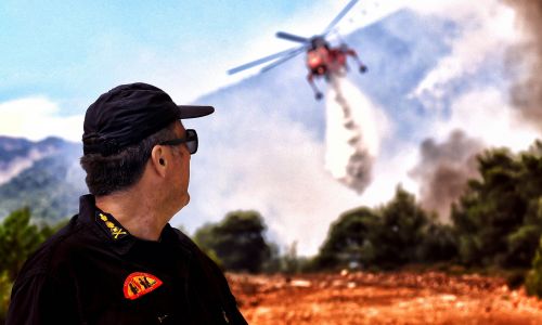 Strażak obserwuje helikopter, który próbuje ugasić pożar w Verori, w pobliżu miasta Loutraki na Peloponezie. Grecja, 24 lipca 2018 r. Fot. PAP/EPA / VASSILIS PSOMAS
