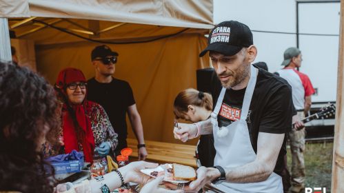 Сяргей Ціханоўскі раздае пасмажаныя ім катлеты на фестывалі «Tutaka»