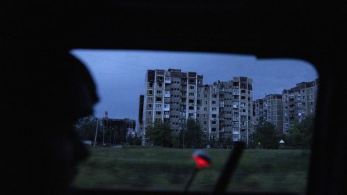 Разбураныя жылыя дамы бачныя з машыны вайскоўцаў, якія праязджаюць каля Пакроўску позна ўвечары. Данецкая вобласць, Украіна. 27 траўня 2025 года. Фота: Jose Colon / Anadolu via Getty Images